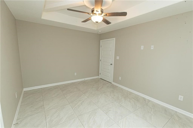 spare room featuring ceiling fan and a raised ceiling