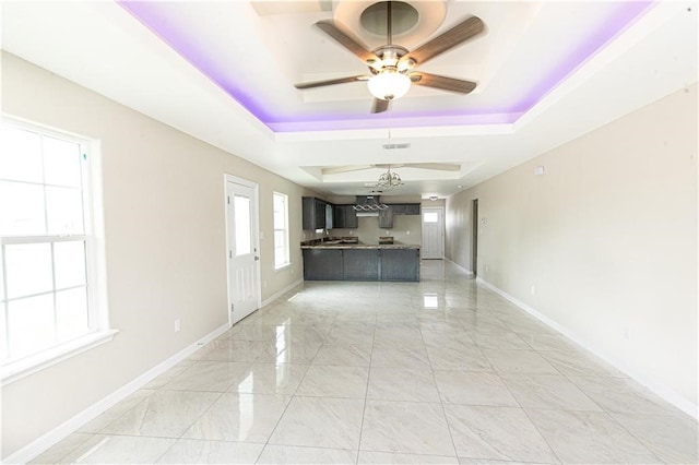 unfurnished living room with a raised ceiling and ceiling fan