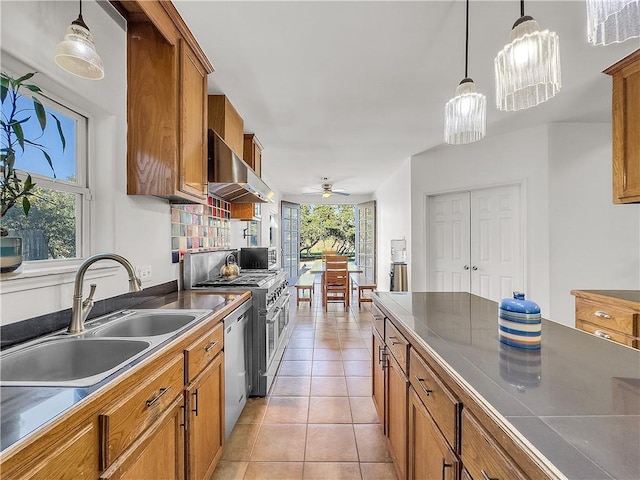 kitchen featuring appliances with stainless steel finishes, sink, hanging light fixtures, light tile patterned floors, and wall chimney exhaust hood