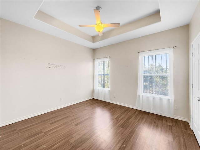 unfurnished room featuring dark wood-type flooring, a raised ceiling, and ceiling fan