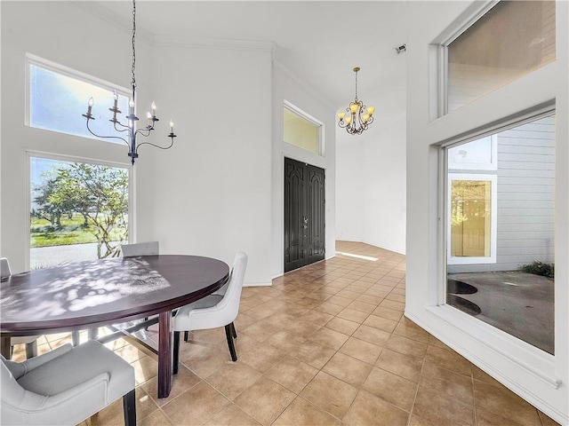 tiled dining area with ornamental molding, a healthy amount of sunlight, a towering ceiling, and a notable chandelier