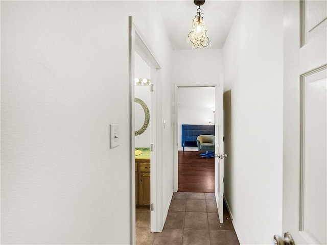 corridor with a notable chandelier and tile patterned floors