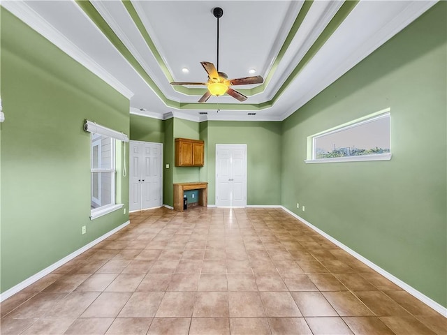 unfurnished living room featuring a raised ceiling, crown molding, light tile patterned floors, and ceiling fan