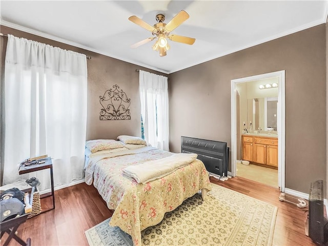 bedroom with hardwood / wood-style flooring, ornamental molding, ensuite bathroom, and ceiling fan