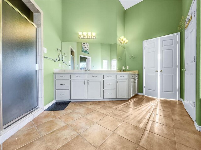 bathroom with tile patterned flooring, vanity, a high ceiling, and walk in shower