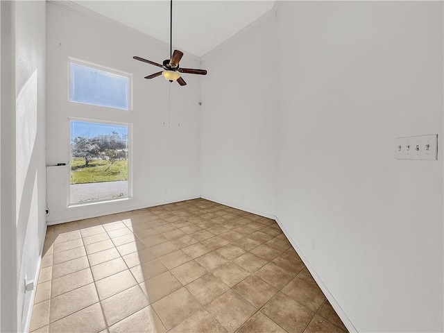 tiled spare room featuring ceiling fan and a towering ceiling