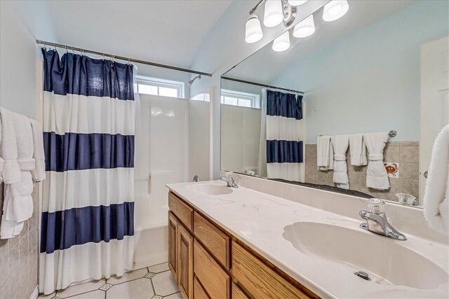 bathroom featuring tile walls, vanity, tile patterned floors, and vaulted ceiling