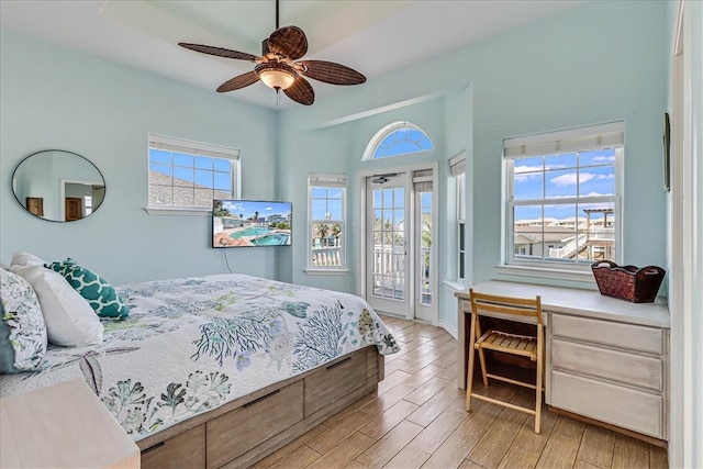 bedroom featuring light hardwood / wood-style floors, ceiling fan, built in desk, and access to exterior