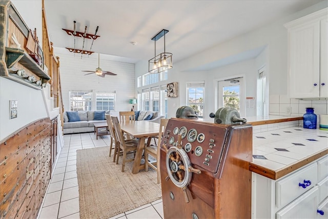 tiled dining area with ceiling fan with notable chandelier