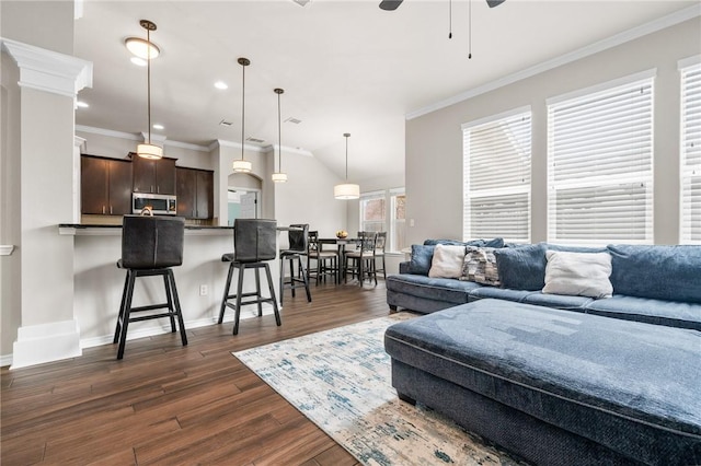 living room featuring dark wood-type flooring, ceiling fan, crown molding, and vaulted ceiling