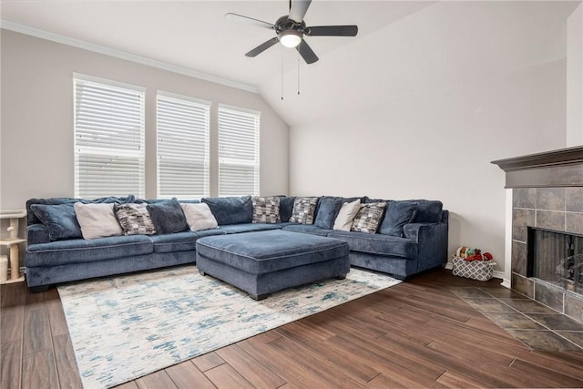 living room featuring vaulted ceiling, a fireplace, dark hardwood / wood-style flooring, ceiling fan, and crown molding