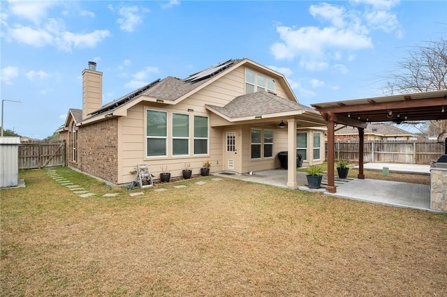 rear view of property featuring a lawn, a patio area, and solar panels