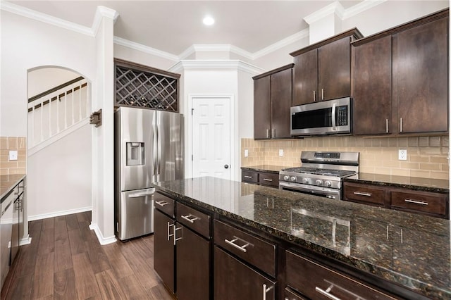 kitchen featuring dark brown cabinetry, dark stone counters, dark hardwood / wood-style floors, stainless steel appliances, and backsplash