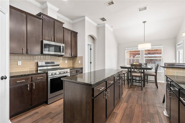 kitchen featuring decorative light fixtures, a center island, dark brown cabinets, stainless steel appliances, and backsplash