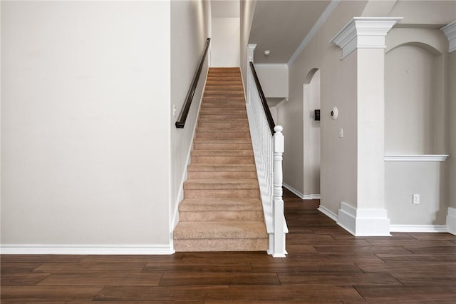 stairway featuring crown molding, wood-type flooring, and decorative columns