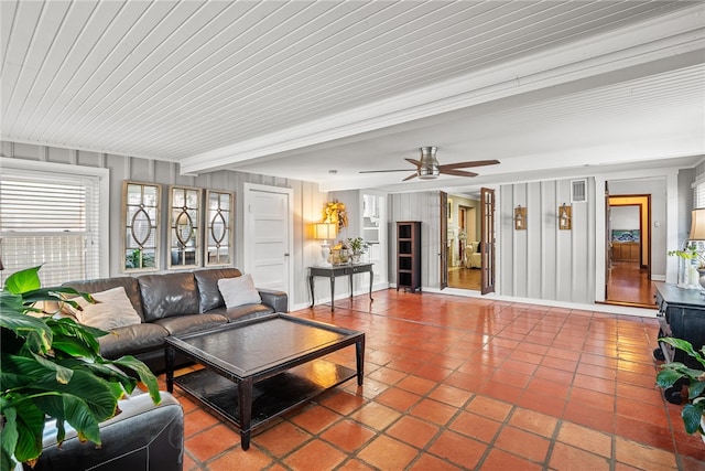 living room with wood walls, beamed ceiling, tile patterned flooring, and ceiling fan