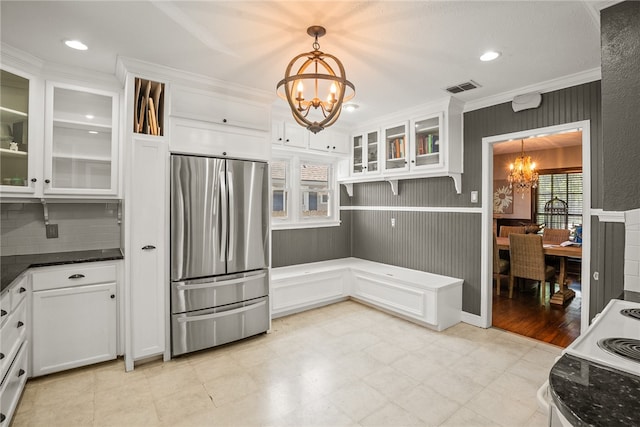 kitchen featuring white cabinetry, pendant lighting, stainless steel refrigerator, and a notable chandelier