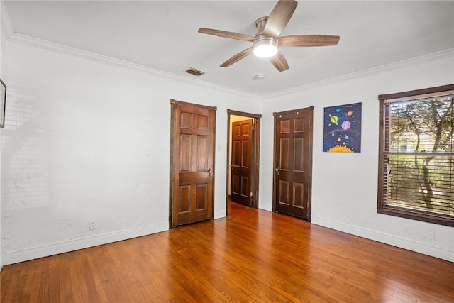 unfurnished bedroom with baseboards, ornamental molding, and wood finished floors