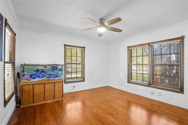 empty room featuring ornamental molding, ceiling fan, baseboards, and wood finished floors