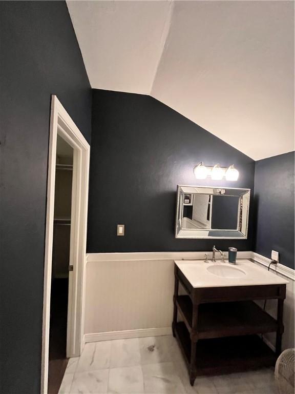 bathroom featuring lofted ceiling, marble finish floor, vanity, and baseboards