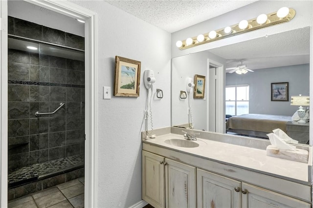 bathroom with tile patterned floors, a textured ceiling, a tile shower, vanity, and ceiling fan