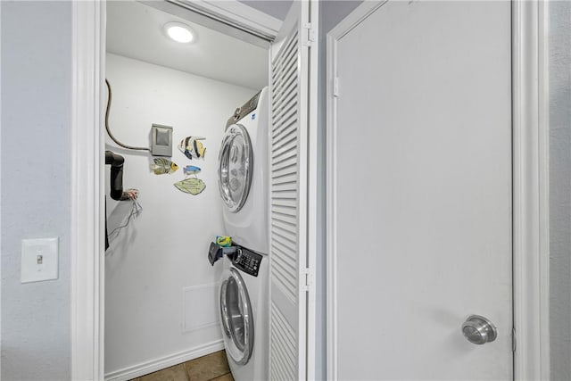 washroom featuring stacked washer and clothes dryer and tile patterned flooring