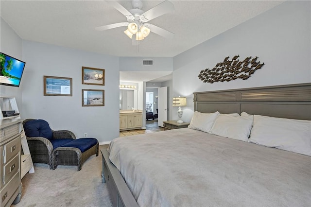 carpeted bedroom featuring ceiling fan and ensuite bath