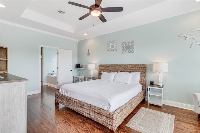 bedroom with dark wood-type flooring, ensuite bathroom, ceiling fan, and a raised ceiling