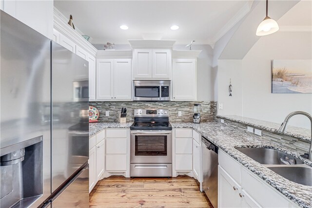 kitchen featuring pendant lighting, appliances with stainless steel finishes, sink, and crown molding