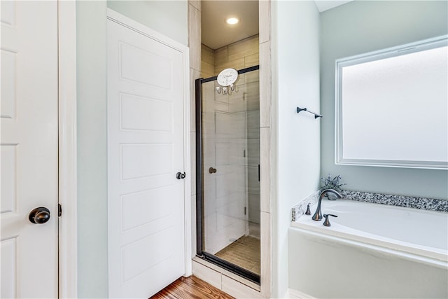 bathroom with hardwood / wood-style floors, a wealth of natural light, and plus walk in shower