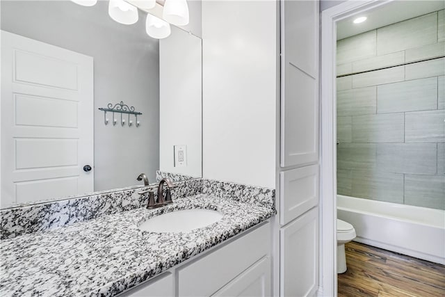 full bathroom with toilet, tiled shower / bath combo, vanity, and hardwood / wood-style flooring