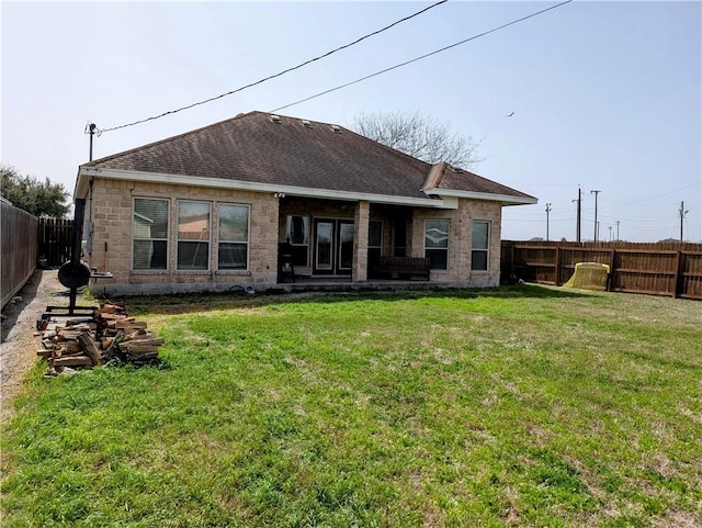 rear view of property featuring roof with shingles, a lawn, and a fenced backyard