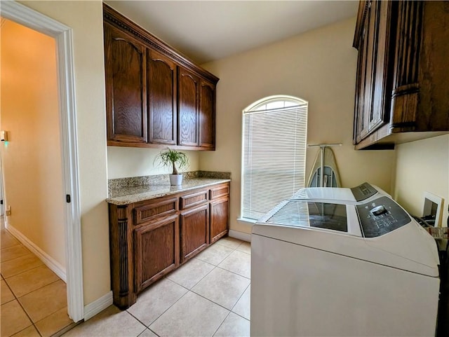 washroom featuring light tile patterned floors, washer and clothes dryer, cabinet space, and baseboards