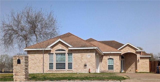 view of front of property featuring a shingled roof, a front yard, and stone siding