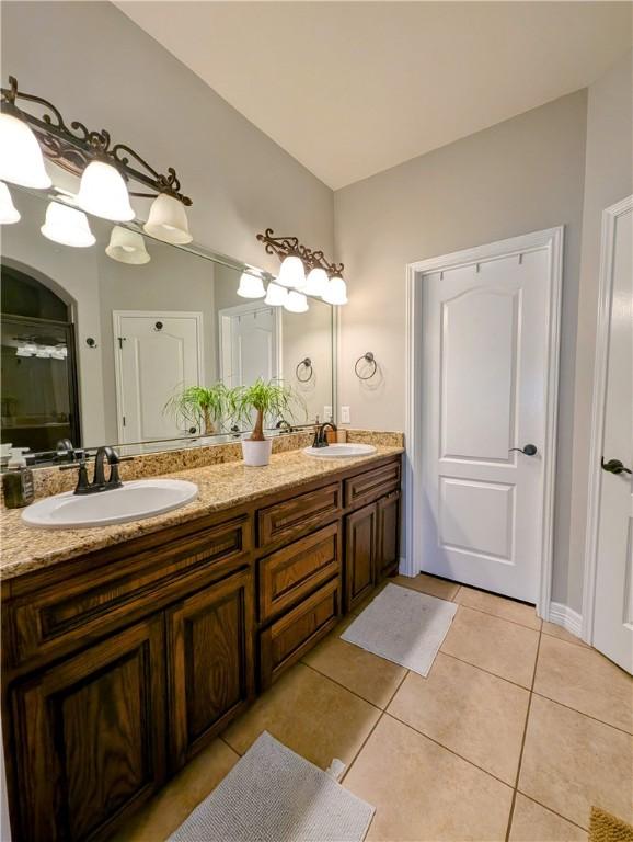 full bath with double vanity, a sink, a shower with door, and tile patterned floors