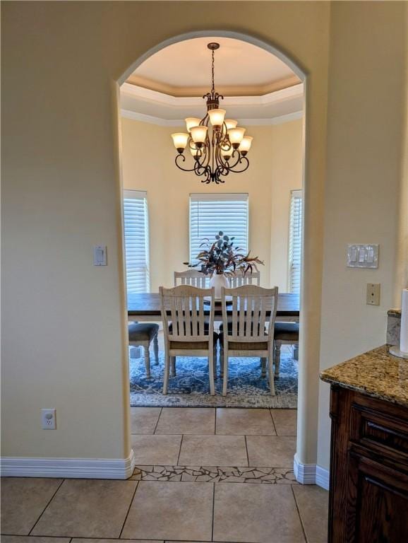 dining room featuring baseboards, a tray ceiling, arched walkways, and light tile patterned flooring