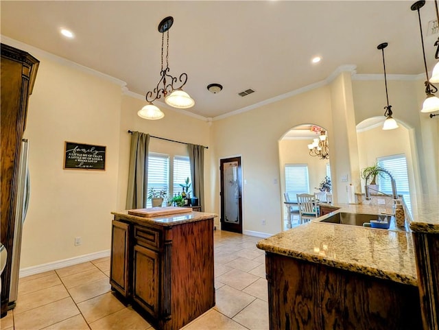 kitchen with ornamental molding, visible vents, a kitchen island, and light tile patterned floors