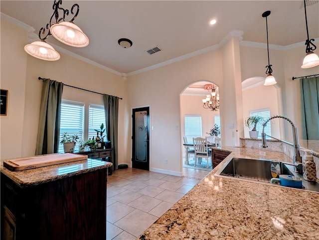 kitchen with a healthy amount of sunlight, ornamental molding, arched walkways, and a sink