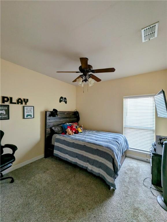 carpeted bedroom featuring baseboards, visible vents, and a ceiling fan