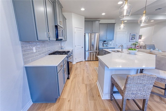 2634 Westeros St, Corpus Christi, TX 78415 - kitchen with appliances with stainless steel finishes, light wood-type flooring, open floor plan, a center island with sink, and tasteful backsplash