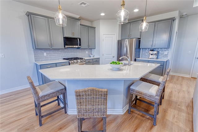 2634 Westeros St, Corpus Christi, TX 78415 - kitchen featuring stainless steel appliances, gray cabinets, a kitchen bar, light wood-type flooring, and decorative backsplash