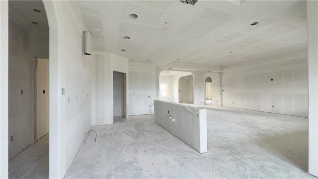 spare room featuring unfinished concrete flooring and arched walkways