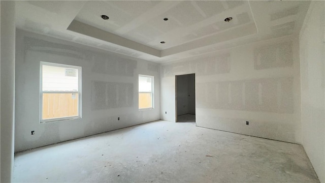 empty room with a tray ceiling and unfinished concrete floors