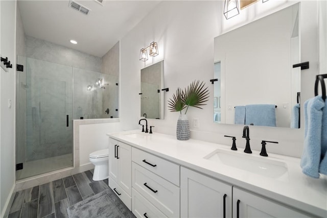 bathroom featuring toilet, a sink, visible vents, and a shower stall