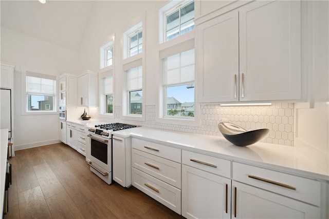 kitchen featuring oven, dark wood-type flooring, white cabinetry, white range with gas cooktop, and backsplash