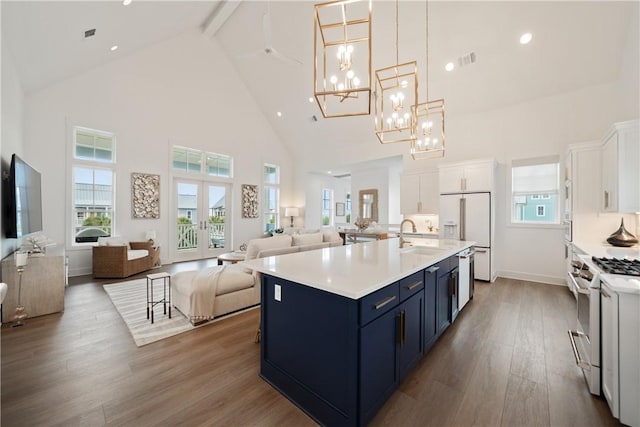 kitchen with appliances with stainless steel finishes, open floor plan, wood finished floors, blue cabinets, and white cabinetry