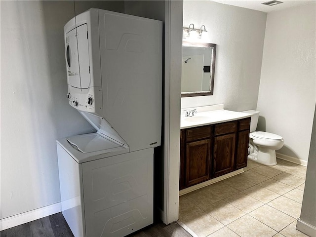 1011 Ennis Joslin Unit 235, Corpus Christi, TX 78412 - washroom featuring stacked washing machine and dryer, light tile patterned floors, and baseboards