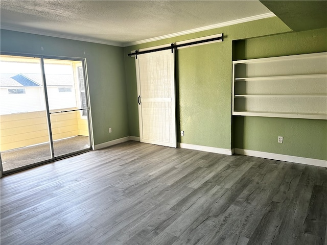 unfurnished bedroom with a barn door, hardwood / wood-style flooring, and ornamental molding