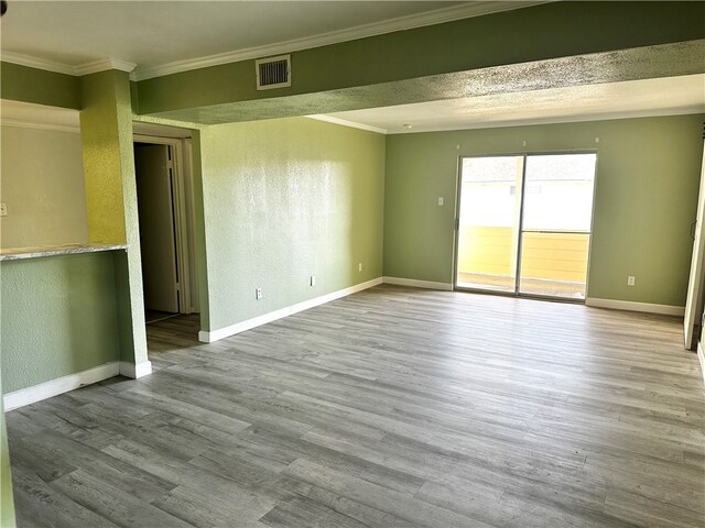 spare room featuring ornamental molding and light hardwood / wood-style flooring