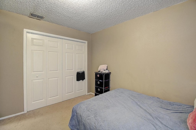 bedroom with light colored carpet, a textured ceiling, and a closet